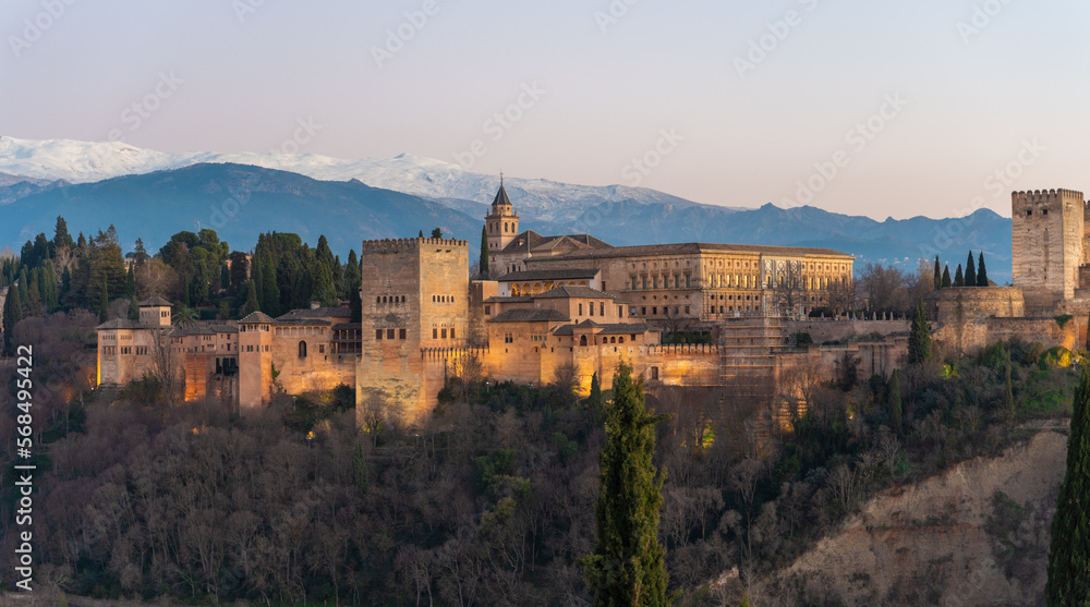 Alhambra historical monument at sunset with Sierra Nevada and its snowy mountains in the background. Photo taken from San Nicolas viewpoint in Granada, Andalusia, Spain