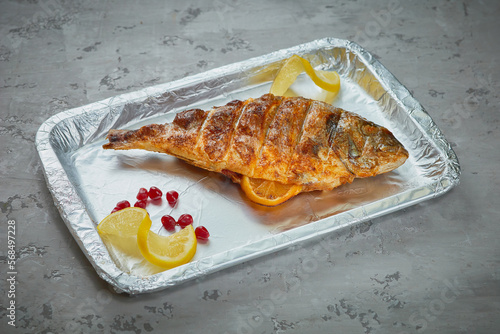 Grilled fish dish on gray concrete background