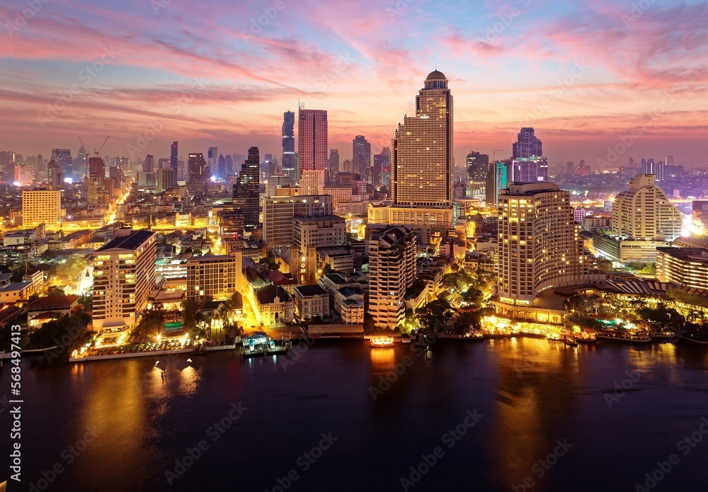 Sunrise scenery of Bangkok City in bird's eye view~ Aerial panorama of Bangkok in morning twilight, with rosy clouds in the sky, light trails on Chao Phraya River & modern skyscrapers by the canal