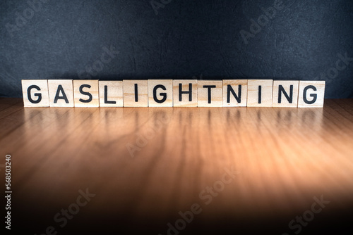 GASLIGHTNING word in wooden letters with balck and red background. Psychological manipulation that causes the victim to question the validity of their though. Loss of confidence and self-esteem.