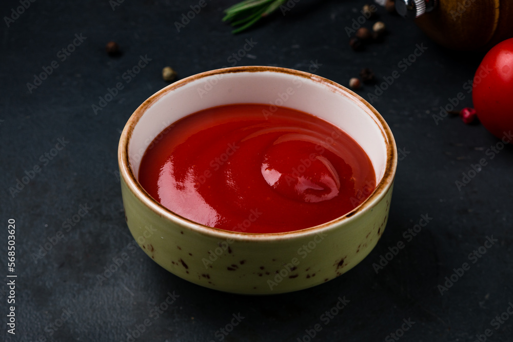 Ketchup sauce in a small ceramic bowl on a dark. Ketchup sauce in a small ceramic bowl on a dark.