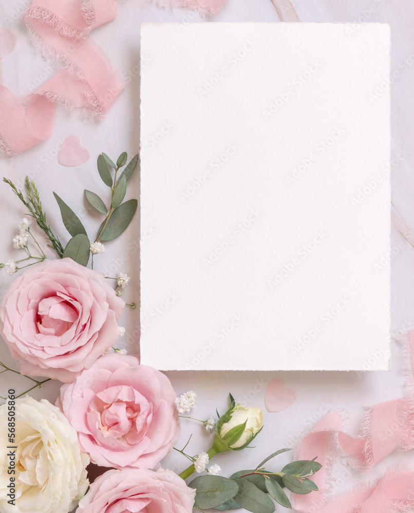 Blank paper card between pink roses and pink silk ribbons on marble top ...