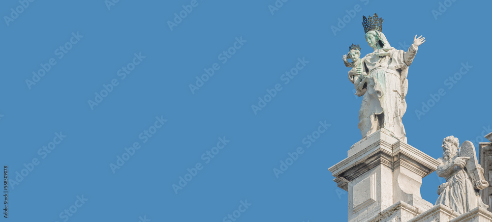 Ancient sculpture of beautiful Venetian Noble Renaissance Era woman with child at Basilica di Santa Maria della Salute in Venice, Italy, at blue sky solid background