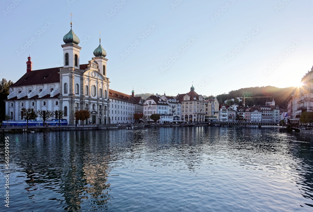 Scenery of Rathaussteg Bridge over Reuss River in Old Town Lucerne, Switzerland with Jesuit Church by the riverside and beautiful reflections on the water before sunset