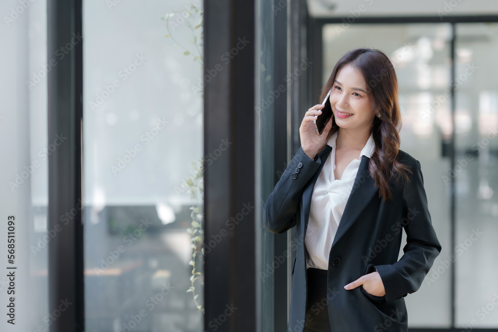 Smiling Asian businesswoman enjoying a phone call with a client in the office. Smiling Asian businesswoman enjoying a phone call with a client in the office.