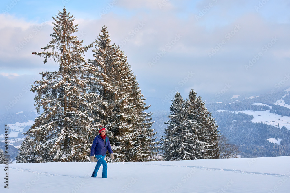 nice and active senior woman snowshoeing in deep powder snow  in the mountains of the Bregenz Forest  Alps near Sulzberg, Vorarlberg, Austria