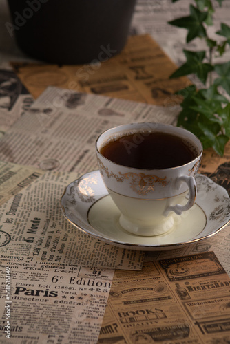 photo a cup of coffee and a sprig of green plant on a background of old newspaper clippings