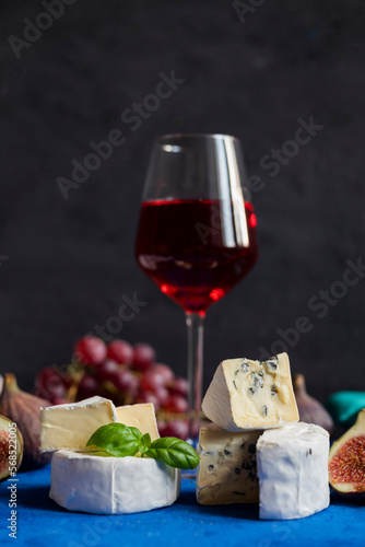 delicious blue brie blue cheese with grapes and figs on a wooden board with a glass of wine