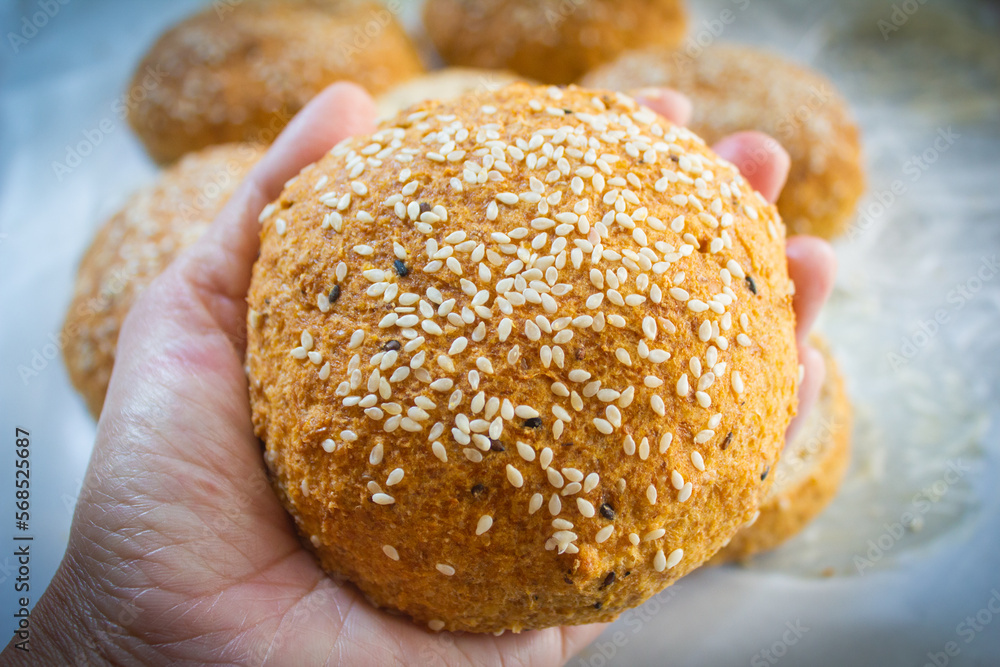 Keto Bun for burger in hand. Low carb buns baked with psyllium husk and flax seeds. Ketogenic diet and gluten free bread for healthy eating concept.