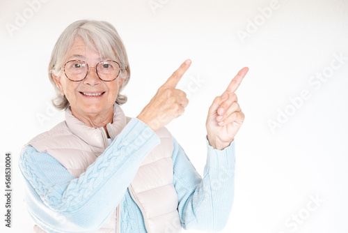 Senior white-haired woman smiling and looking at the camera pointing with hands and fingers to the side. Attractive mature lady isolated on white background, copy space