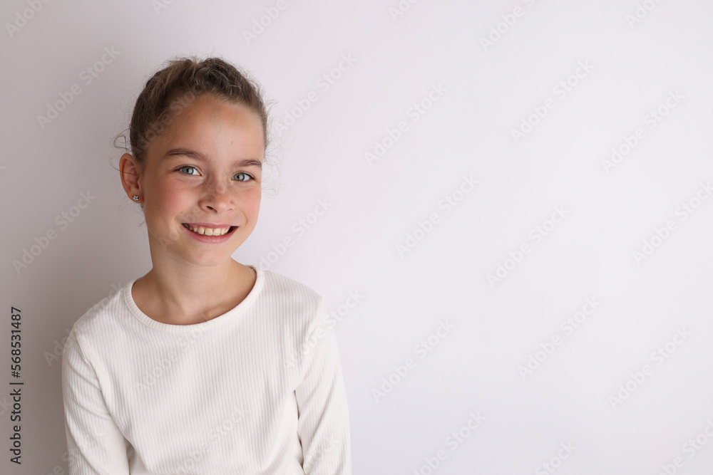 Little emotional teen girl in white shirt 11, 12 years old on an isolated white background. Children's studio portrait. Place text, to copy space for inscription, advertising children's goods. Little emotional teen girl in white shirt 11, 12 years old on an isolated white background. Children's studio portrait. Place text, to copy space for inscription, advertising children's goods.
