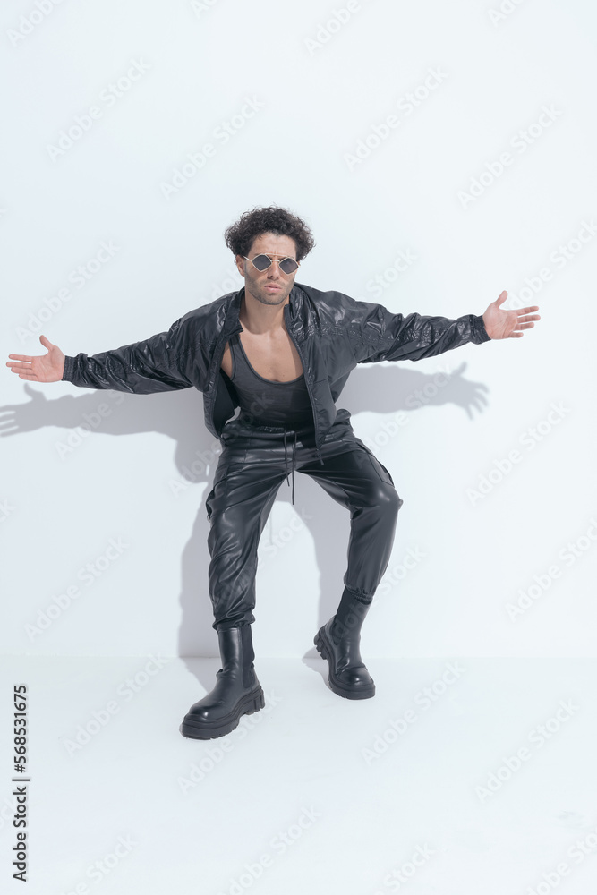 fashion model with curly hair wearing leather suit and opening arms fashion model with curly hair wearing leather suit and opening arms