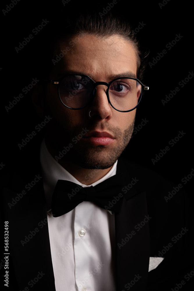 elegant young man with glasses wearing black tuxedo and posing elegant young man with glasses wearing black tuxedo and posing