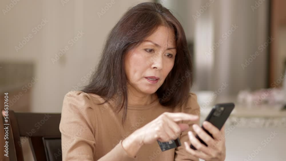 Attractive woman relaxing shopping online with e-commerce credit card is excited with success of buying sitting in peaceful leisure home. Mature asian has healthy lifestyle. Attractive woman relaxing shopping online with e-commerce credit card is excited with success of buying sitting in peaceful leisure home. Mature asian has healthy lifestyle.