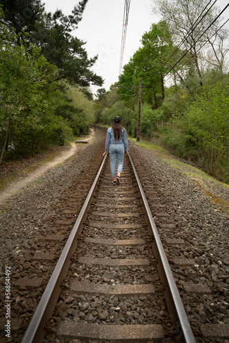 woman in blue jeans walking along the railroad in spring