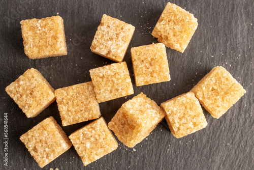Several cubes of brown sugar, close-up, on a slate board, top view.