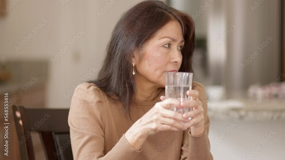 Attractive woman relaxing drinking water sitting in comfortable leisure home. Mature asian has healthy lifestyle. Attractive woman relaxing drinking water sitting in comfortable leisure home. Mature asian has healthy lifestyle.