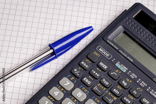 Close-up of a calculator on squared paper background for math, physics, engineering or business homework and tax and finance calculations 
