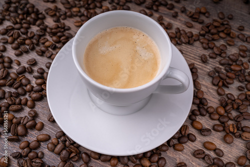 Coffee crema in a white cup with coffee beans in the background