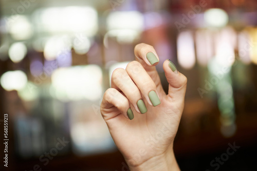 light green matte manicure, hands on a blurred background. Close-up of a young woman's hands with a light green matte manicure with rings on her fingers