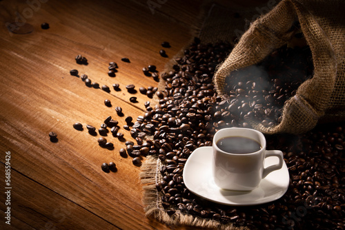 Coffee break background. Hot coffee in cup and roasted coffee beans on a wooden table. Copy space