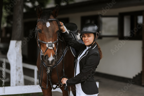 Girl taking care of her horse before horse riding. Equestrian sport. © JJ Studio