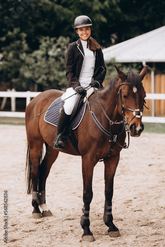 young beautiful woman rides a horse wearing a helmet. Horseback Riding. © JJ Studio