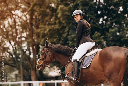 Equestrian sport - a young girl is riding a horse © JJ Studio