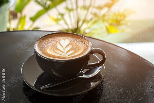 Obraz na płótnie Hot coffee latte with latte art milk foam in cup mug on black wood desk on top view. As breakfast In a coffee shop at the cafe,during business work concept w salonie