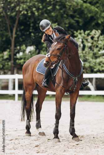 Young woman in special uniform and helmet riding horse. Equestrian sport - dressage © JJ Studio