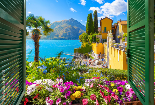 View from an open window with shutters overlooking Italian gardens  Lake Como and the mountains of North Italy  at Varenna  Italy.