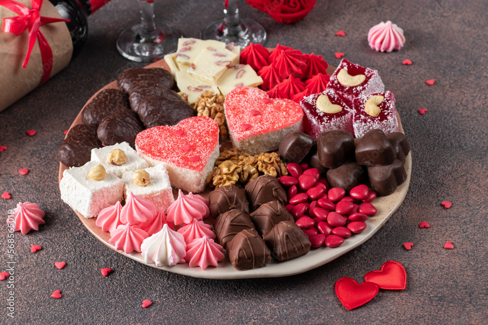 Sweet romantic plate with jelly cakes, chocolate, walnuts, meringue and Turkish delight on Valentine's Day on brown background