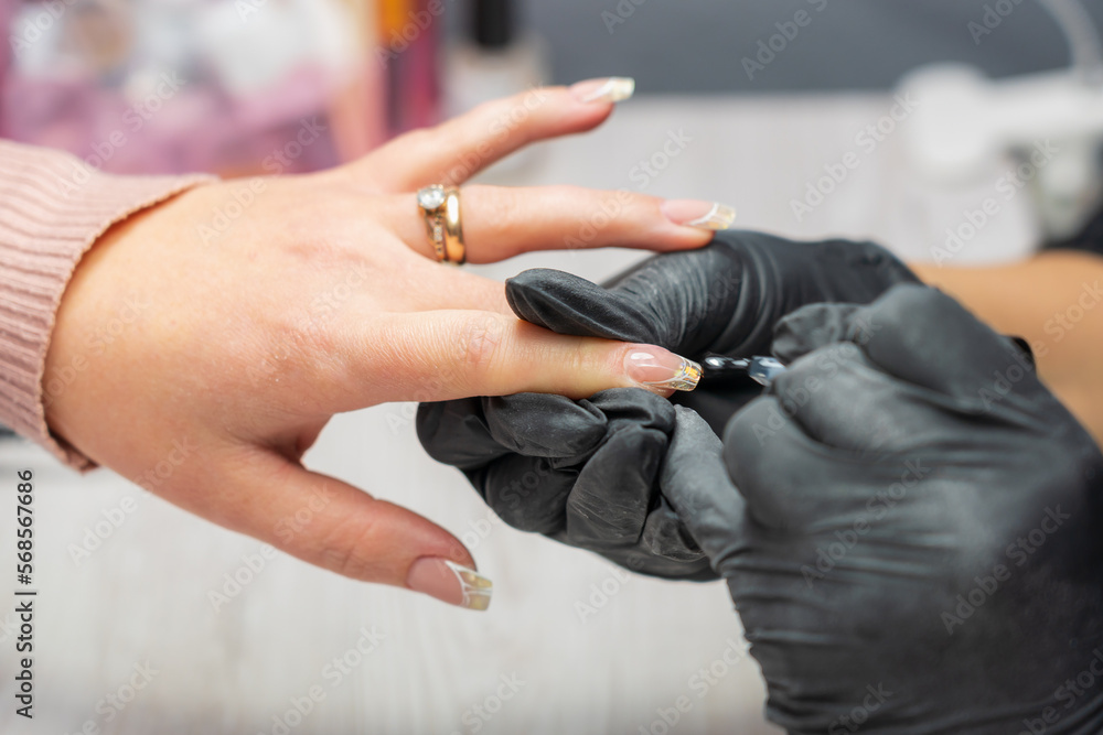 Hands close-up in a beauty salon on a manicure. Background, selective focus Hands close-up in a beauty salon on a manicure. Background, selective focus