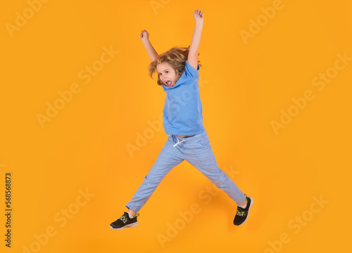 Full length of excited kid jumping. Full length photo of kid boy jump high wear casual checkered shirt isolated on yellow background. Portrait of jumping boy. Kid jumping, having fun.