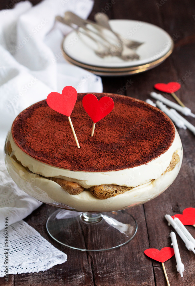 Traditional Italian dessert tiramisu served in a glass vase decorated with paper hearts.