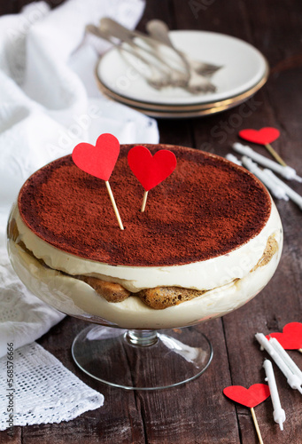 Obraz na płótnie Traditional Italian dessert tiramisu served in a glass vase decorated with paper hearts. w salonie