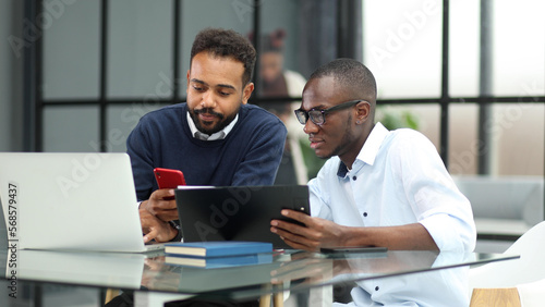 Businessman Using Laptop At Desk In Busy Office