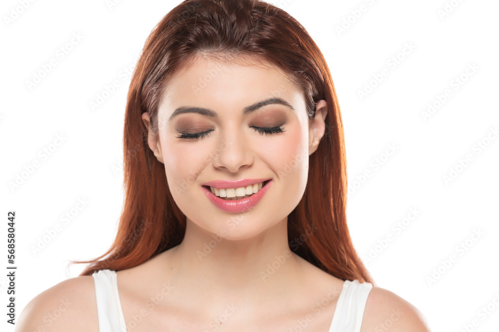 Portrait of smiling beautiful woman with long straight ginger hair makeup and closed eyes on a white studio background Portrait of smiling beautiful woman with long straight ginger hair makeup and closed eyes on a white studio background