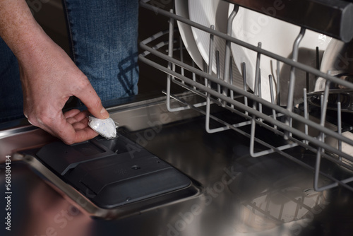 Woman placing detergent pod into dishwasher soap dispenser closeup photo