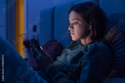Woman chatting and surfing on internet with smartphone late at night, because of blackout
