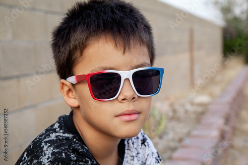 Portrait of boy sitting in summer sunglasses on 4th of July Independence Day