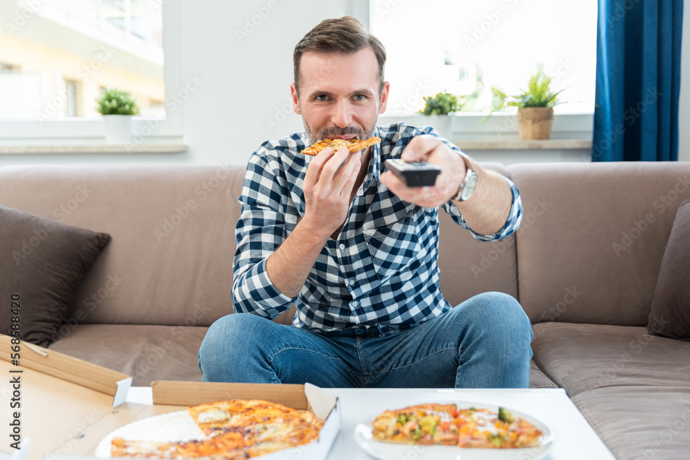Man with remote control, watch TV, eating pizza. Man with remote control, watch TV, eating pizza.