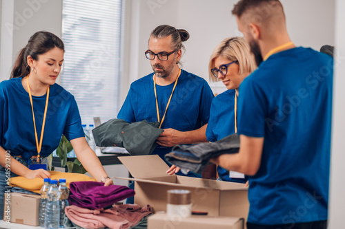 Diverse volunteers working in a charity donation center and packing clothes and food