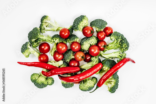 A bunch of red hot peppers with pieces of broccoli and ripe cherry tomatoes