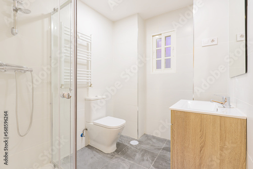 bathroom with a wooden sink below a frameless wall-hung mirror  a walk-in shower with screens  a heated towel rail and white wooden doors