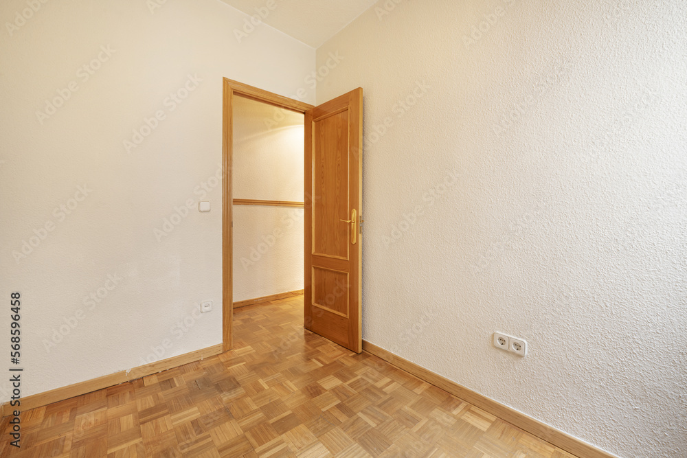 Empty room with gotelet white painted walls, oak wooden doors and matching skirting boards and oak parquet slatted floors laid in a checkerboard pattern Empty room with gotelet white painted walls, oak wooden doors and matching skirting boards and oak parquet slatted floors laid in a checkerboard pattern