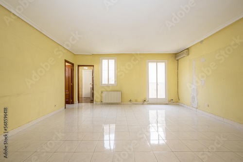 Empty room with aluminum radiator  sapele doors to access other rooms and white aluminum doors to a balcony with views