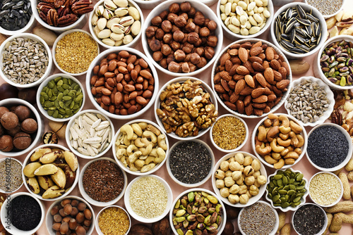 Colorful mix of various nuts and seeds: peanut and cashew, hazelnut and almond, pine nuts and walnut; healthy diet snack; vegan food background	