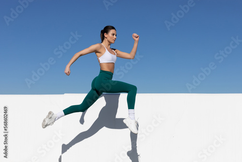 athletic woman running or jumping in the air, focus on face, space for text