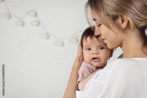 Mother hugging her cute little baby indoors, space for text